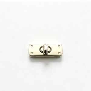Close-up of a high-polish light gold rectangular twist lock featuring four decorative corner rivets for luxury handbags, custom manufactured by Wahkoi Metal