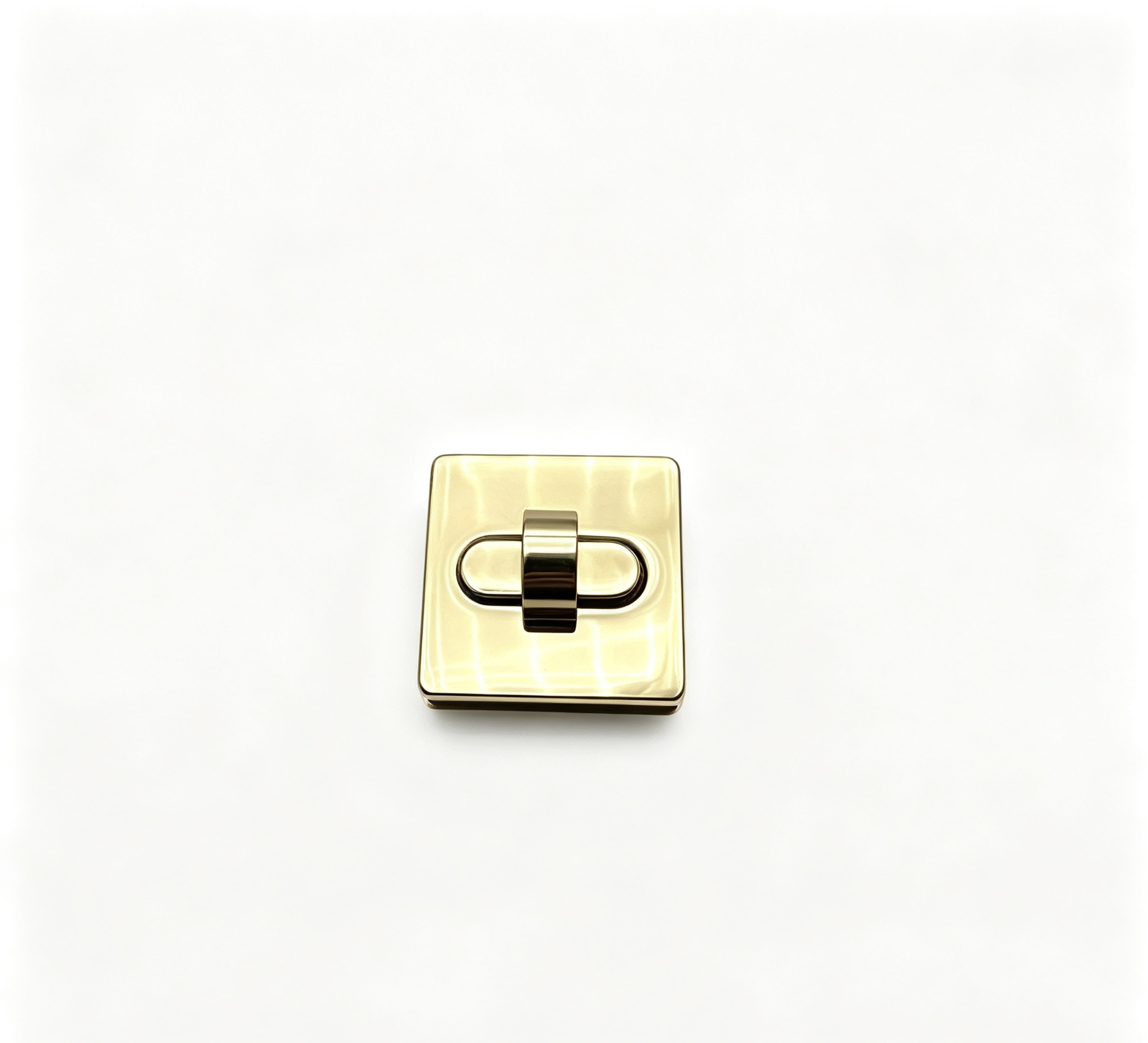Close-up of a high-polish light gold soft square twist lock featuring a recessed oval center for luxury handbags, custom manufactured by Wahkoi Metal