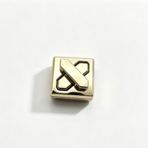 Close-up of a high-polish light gold square twist lock featuring a geometric X-shape turn mechanism for luxury handbags, manufactured by Wahkoi Metal